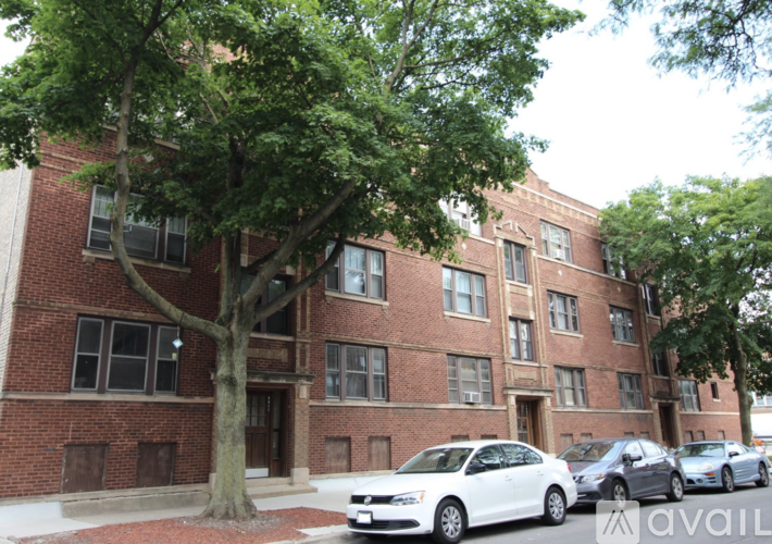A white car is parked in front of a brick building.