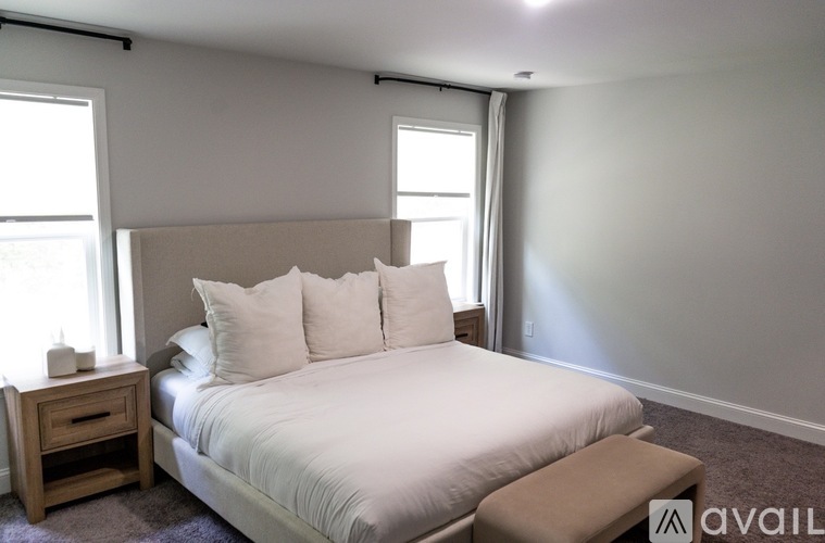 A bedroom with a large bed and a nightstand with a drawer.