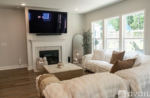 A living room with a fireplace and a television mounted above it.