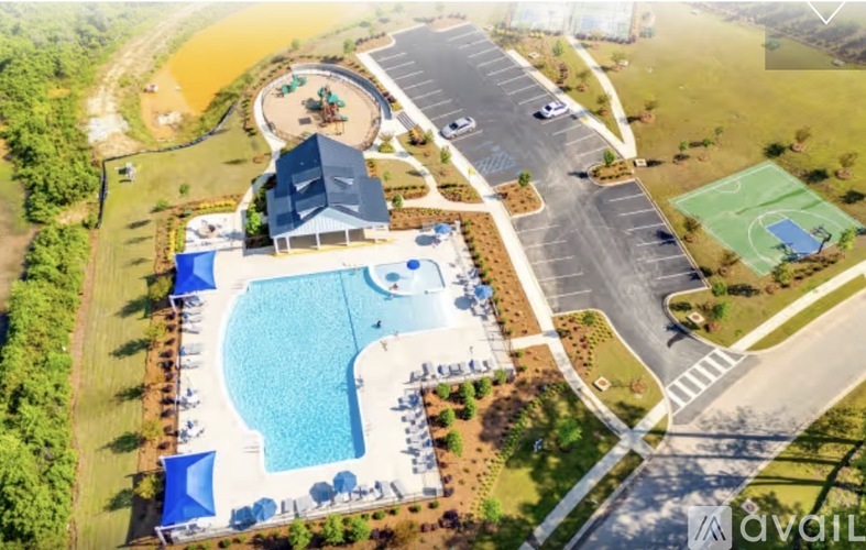 An aerial view of a pool with a blue umbrella and a basketball court.