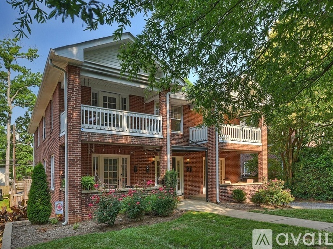 A red brick house with a white porch and a green lawn.