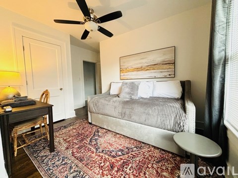 A bedroom with a bed, desk, and rug.
