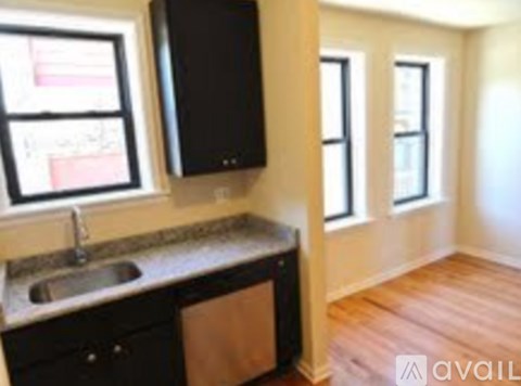A kitchen with black cabinets and a sink under a window.