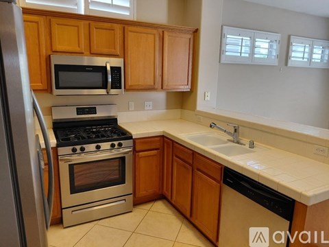 A kitchen with wooden cabinets and a stainless steel refrigerator.