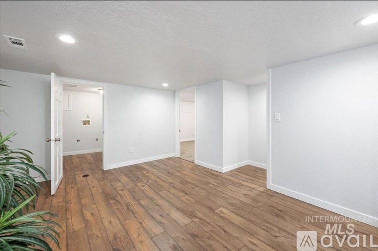 A room with wooden flooring and white walls.