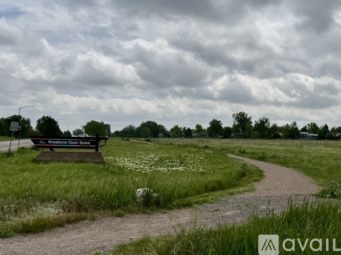 A bench with a sign that reads "Krabbespace" sits in a field with a dirt path leading to it.