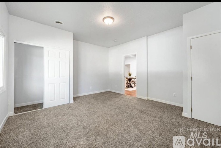 A spacious room with carpeted floor and white walls.