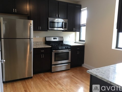 A kitchen with black cabinets and a stainless steel refrigerator.