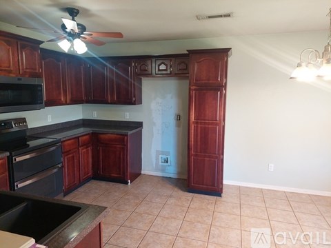 A kitchen with brown cabinets and a black counter top.