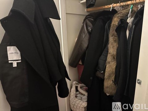 A black coat with a white tag hangs on a rack next to other coats.