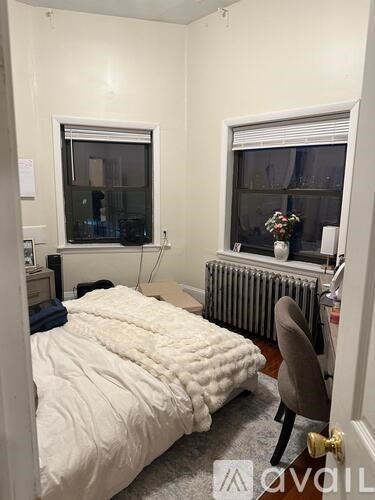 A bedroom with a bed, chair, and window.