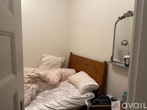 A bedroom with a bed, pillow, and a mirror on the wall.