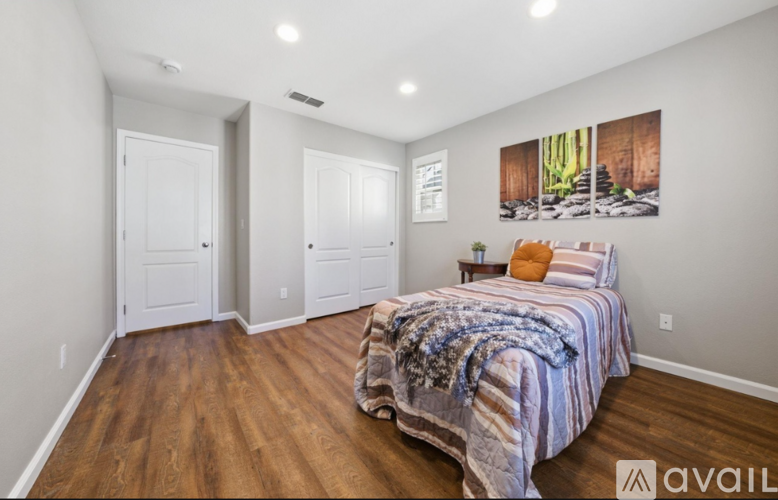 A bedroom with a bed covered in a striped blanket and a painting on the wall.