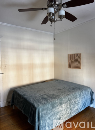 A bedroom with a bed, ceiling fan, and a picture on the wall.
