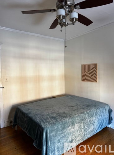 A bedroom with a bed, ceiling fan, and a picture on the wall.