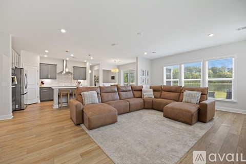 A modern living room with a large sectional sofa and a kitchen area in the background.