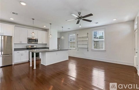 A spacious kitchen with white cabinets and a wooden floor.