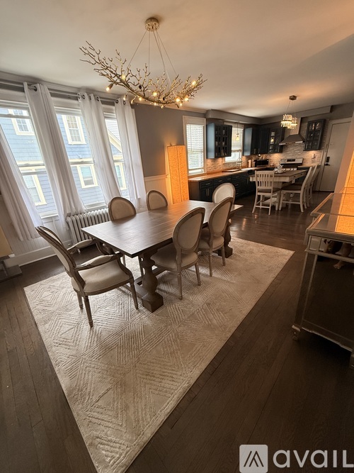 A dining room with a table set for six with a chandelier above.