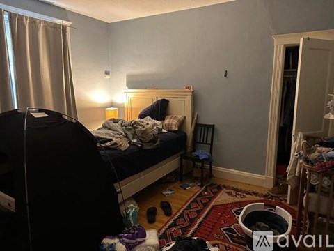 A bedroom with a bed, chair, and a rug on the floor.