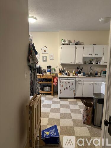 A kitchen with white cabinets and a checkered floor.