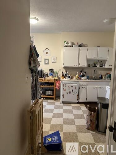 A kitchen with white cabinets and a checkered floor.