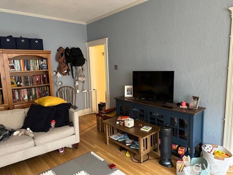 A living room with a grey couch, a wooden entertainment center, and a bookshelf.