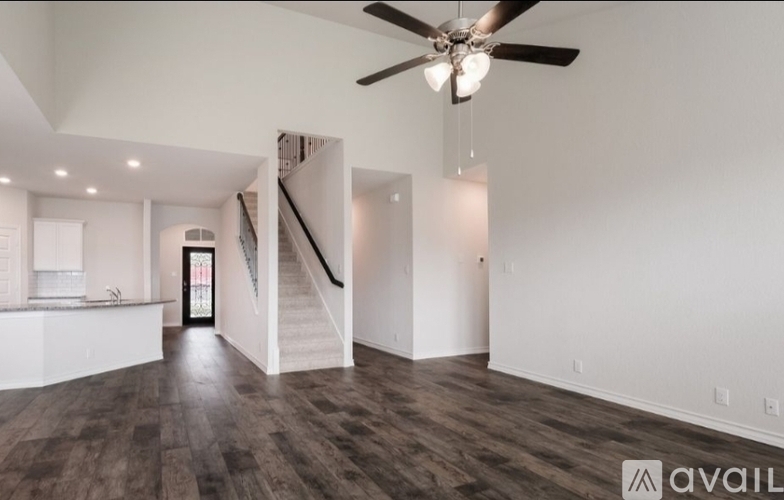 A spacious room with a staircase and a ceiling fan.