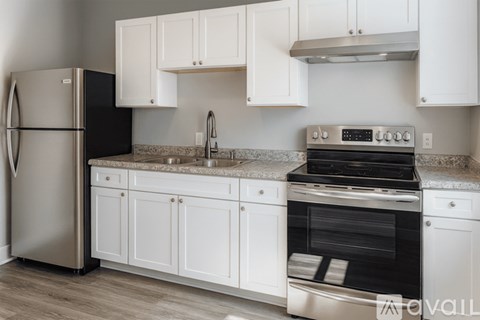 A kitchen with white cabinets and a black fridge.