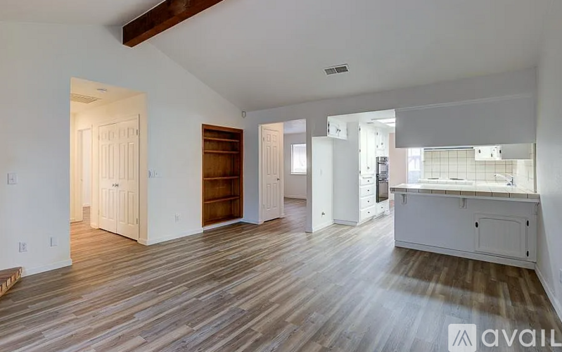 A spacious room with wooden floors and white walls.