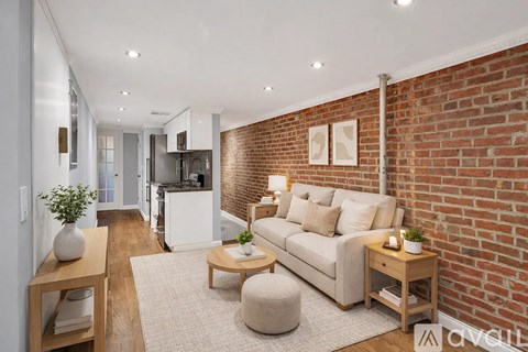 A living room with a white couch and a brick wall.