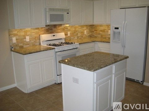 A kitchen with white cabinets and a granite countertop.