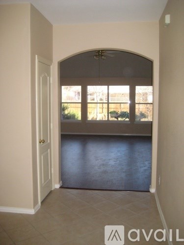 A room with a large arched window and a view of a fence and trees outside.