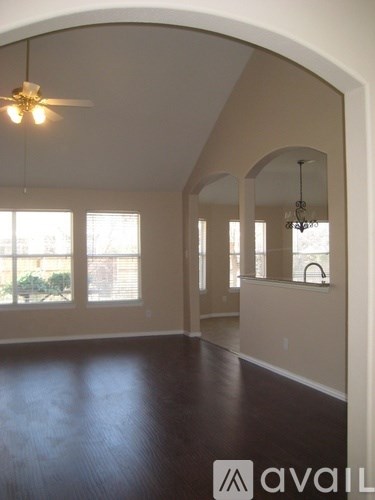 A spacious room with wooden floors and a ceiling fan.