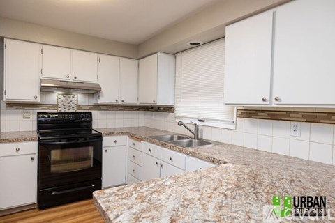 A kitchen with a black oven and white cabinets.