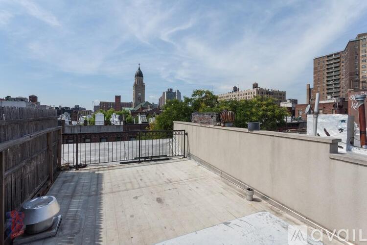 A rooftop with a metal railing and a view of a city skyline.