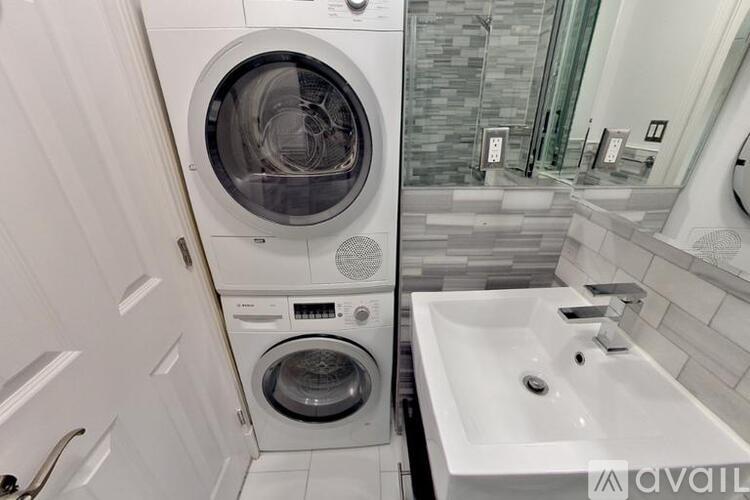 A modern bathroom with a washing machine built into the wall.