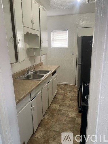 A kitchen with white cabinets and a black refrigerator.