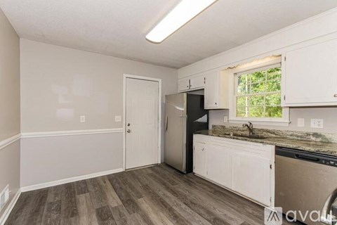 A kitchen with white cabinets and a black fridge.