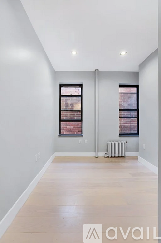 A spacious room with a window and a radiator on the floor.
