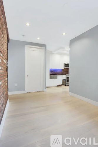A room with a white door and a brick wall on the left side.