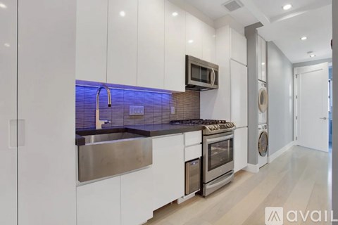 A modern kitchen with white cabinets and stainless steel appliances.