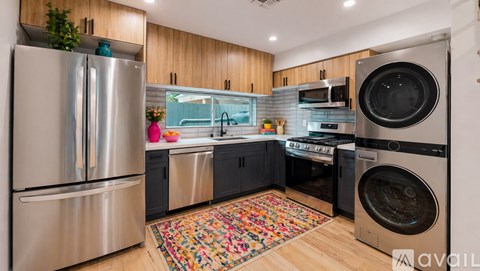 A modern kitchen with a stainless steel refrigerator and a washing machine.