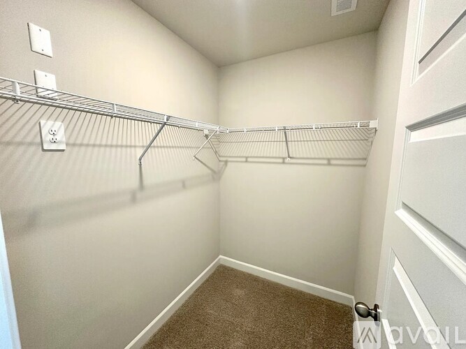 A small, empty closet with a carpeted floor and white walls.