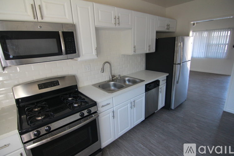 A kitchen with white cabinets and a black refrigerator.