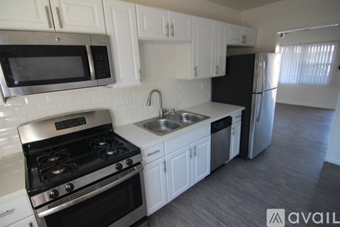 A kitchen with white cabinets and a black refrigerator.