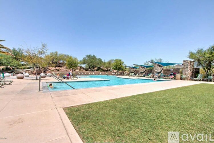 A large outdoor swimming pool surrounded by a grassy area and trees.