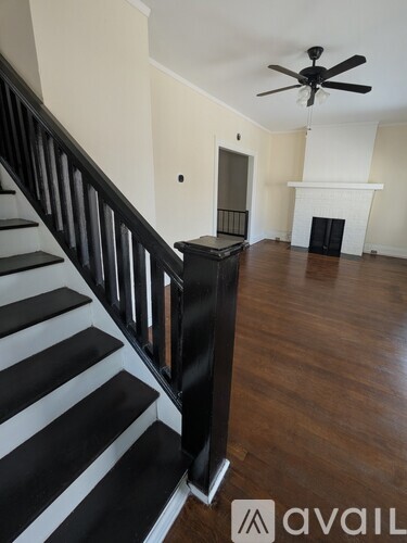 A staircase with black and white steps leads to a living room with a fireplace.