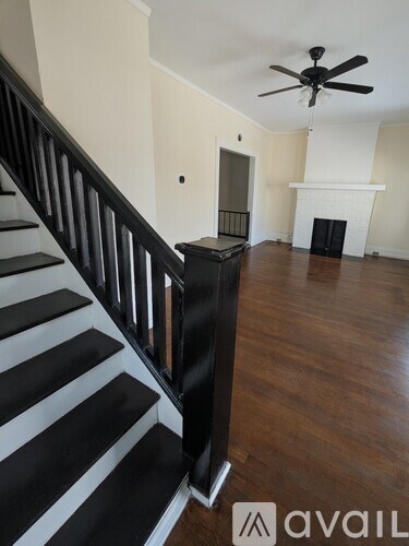 A staircase with black and white steps leads to a living room with a fireplace.
