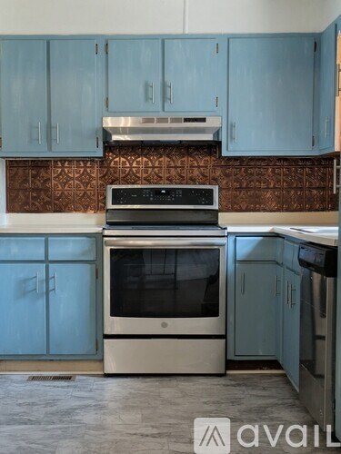 A kitchen with blue cabinets and a stove top oven.