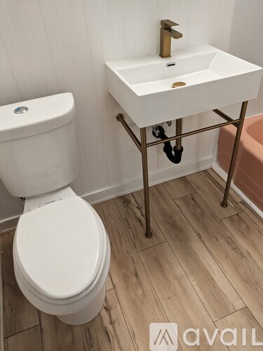 A white toilet sits next to a white sink on a stand in a bathroom.